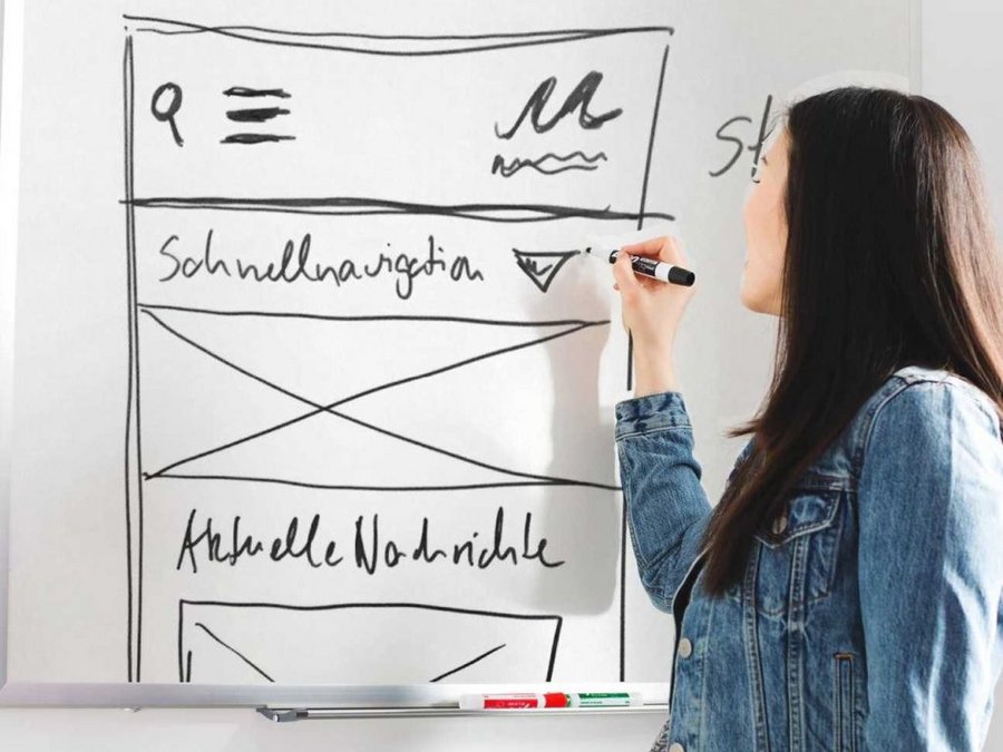 Großansicht Eine junge Frau skizziert den groben Aufbau einer Website in der Smartphone-Ansicht