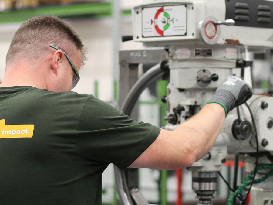 Ein Mann mit Schutzbrille und Sicherheitshandschuhen arbeitet an einer Maschine
