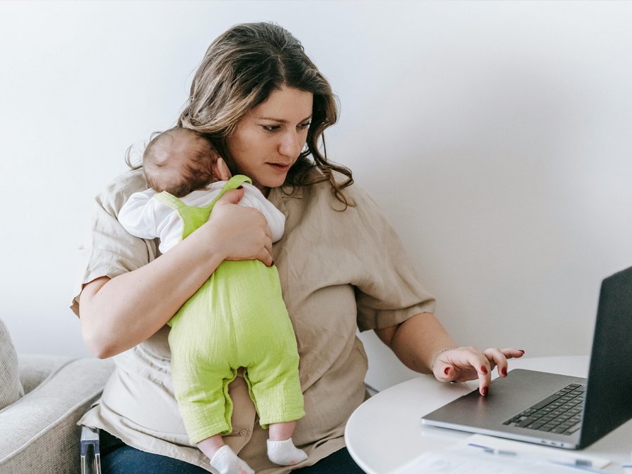 Eine junge Frau sitzt entspannt auf dem Boden, vor sich einen Laptop