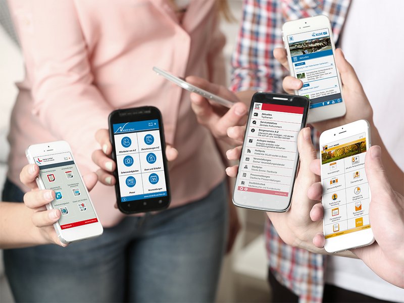Menschengruppe zeigt Handys mit verschiedenen Ansichten der App
