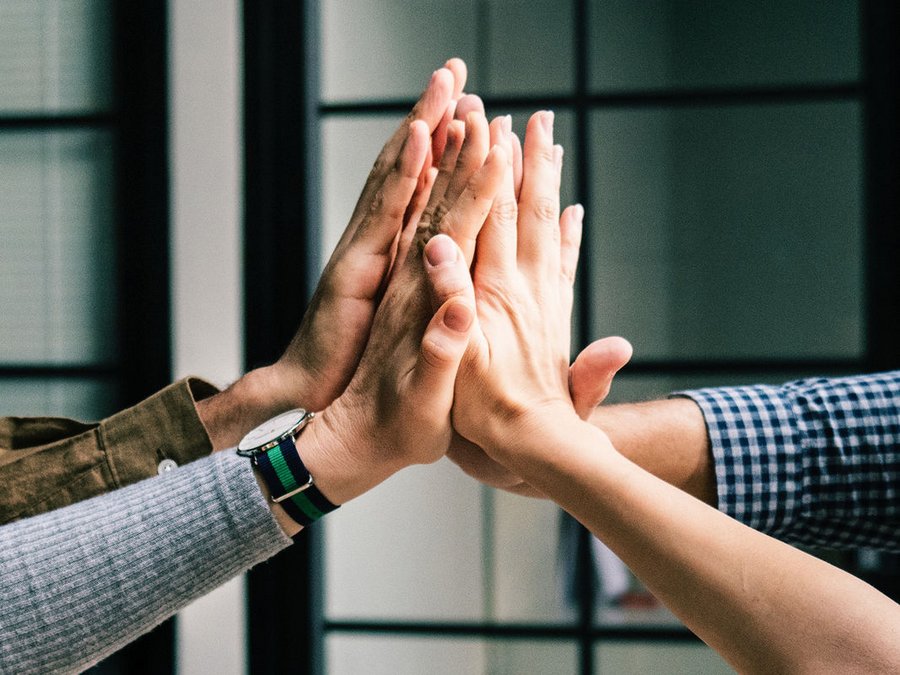 Großansicht Detailaufnahme Hände. Vier Personen klatschen sich ab.
